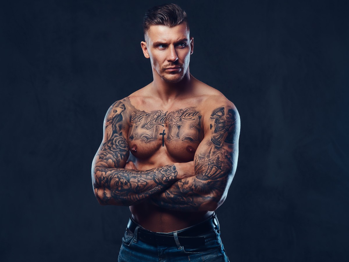 A muscular tattooed man over dark background.
