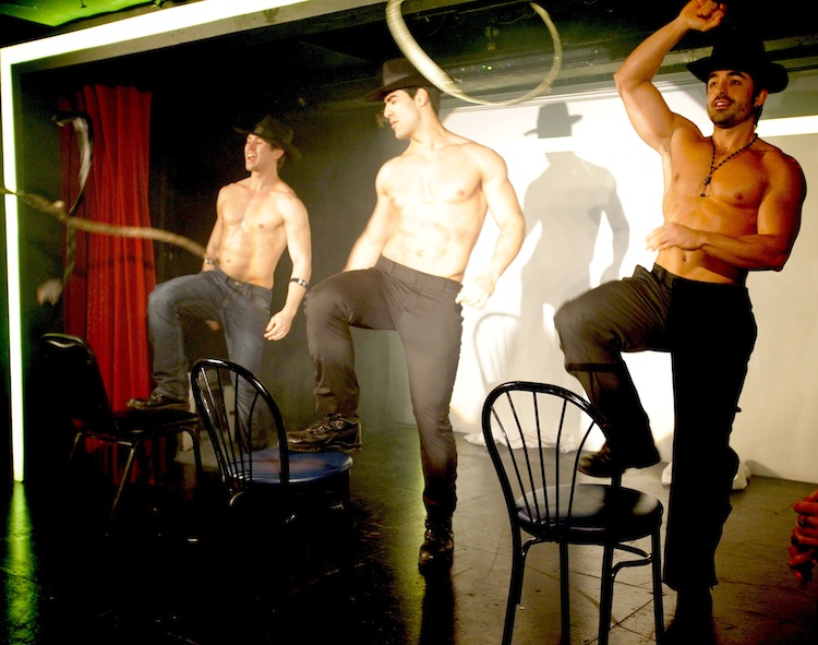 _MG_7104 Three shirtless men wearing hats perform on stage with chairs and a rope.